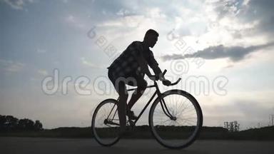 年轻男子骑着老式<strong>自行车</strong>的<strong>剪影</strong>，背景是美丽的天空。 骑<strong>自行车</strong>的人